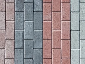 Paving with stones in a garden using rectangular, multi-coloured stone blocks arranged in a neat, uniform pattern.