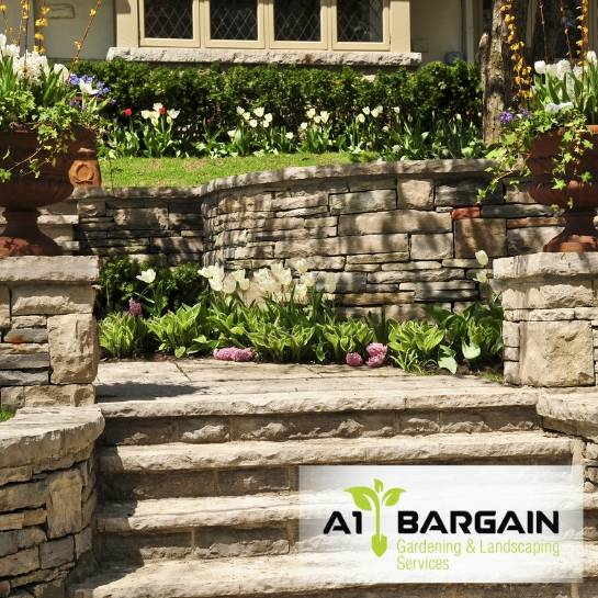 Retaining Walls Sydney: Stone retaining wall with stairs and landscaping, showcasing professional installation.