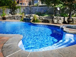 Relaxing backyard with a pool and neat paving around pool area, perfect for summer.