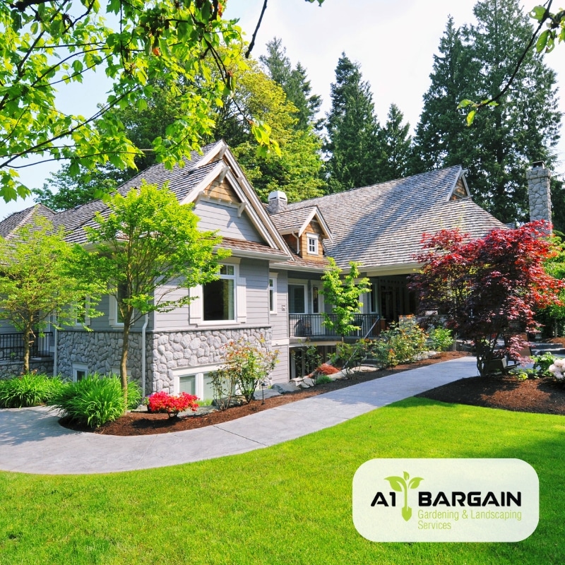 Front yard with a landscaped garden featuring a lush green lawn, flowers, and a white house. Garden landscaping ideas.